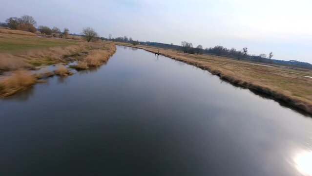 FPV footage of a drone flying low over a river and water surface in nature.