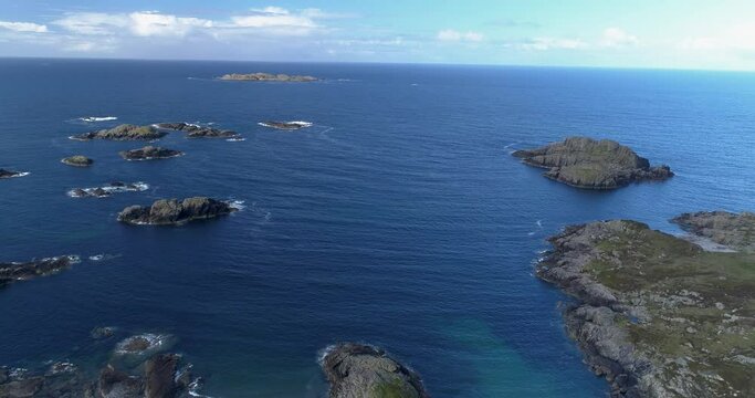 An aerial pull-back shot above the sea revealing the beach and the coastline of Iona