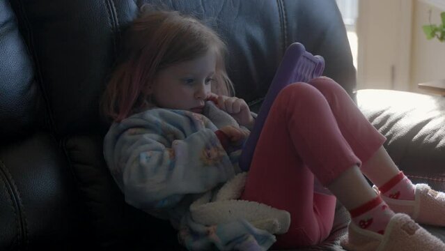 Female child playing and learning on a tablet at home