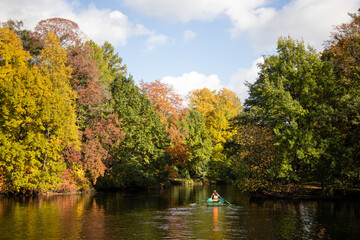 Fototapeta premium Couple rowing a boat on the lake in autumn park