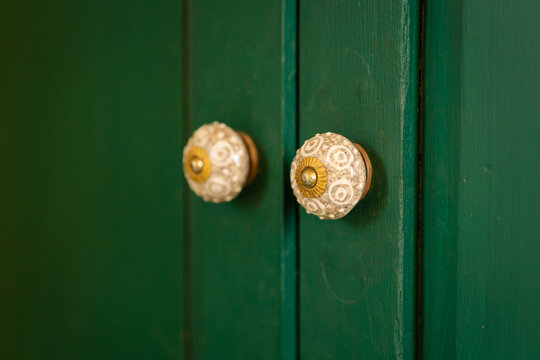 Antique classic white ceramics with the brass door knob on the green wooden door is a vintage design home and living interior building. Architecture old building decoration concept.