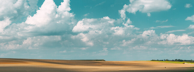 Tractor Plowing Field In Spring Season Sunny Day. Bright Clouds On Background. Countryside Rural...