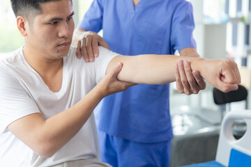 Fototapeta premium Doctor or Physiotherapist working examining treating injured arm of athlete male patient, stretching and exercise, Doing the Rehabilitation therapy pain in clinic.