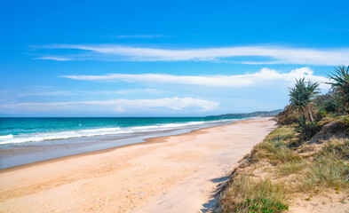Stunning panoramic view of the ocean and beautiful waves rolling in on a pristine sandy beach.  