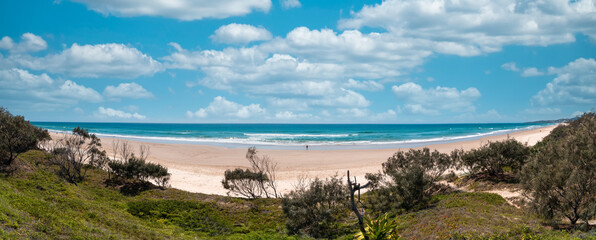 Breathtaking wide angle panorama of the beach with rolling waves of the Pacific Ocean. Scenic landscape of the Peregian Beach on the Sunshine Coast, Australia. Beautiful cloudscape.