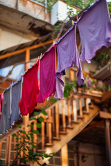 multi-colored clothes are dried on a rope in an old courtyard