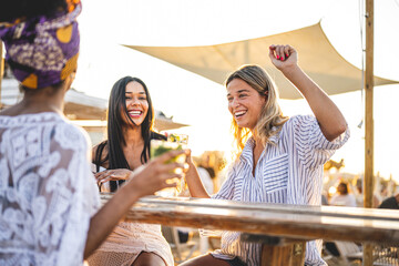 Happy girls having fun drinking alcohol free mojito at cocktail bar on the beach, summer vacation...