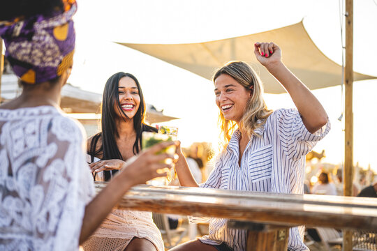Happy girls having fun drinking alcohol free mojito at cocktail bar on the beach, summer vacation and youth lifestyle concept