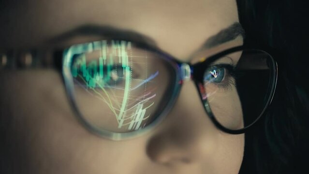Reflection in women's glasses of trading charts. A business woman broker studies the analytics of the company's finances. High quality 4k footage