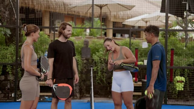 A lot of people greet each other padel tennis sport field. Player team bump opponent fists before game match. Joyful competitor wish good luck talk. Fun girl person. Rival man big play. Guy work court