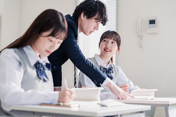 教室で先生に質問をする高校生