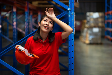 Tired hot wiping sweat. Warehouse female staff worker working hard standing by goods shelf in large...