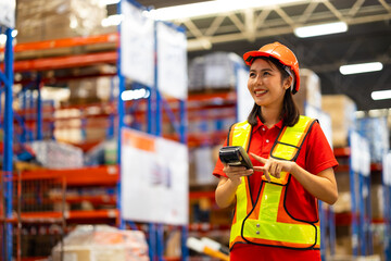 Warehouse female staff worker wearing hardhat helmet working on barcode scanner handheld at warehouse factory