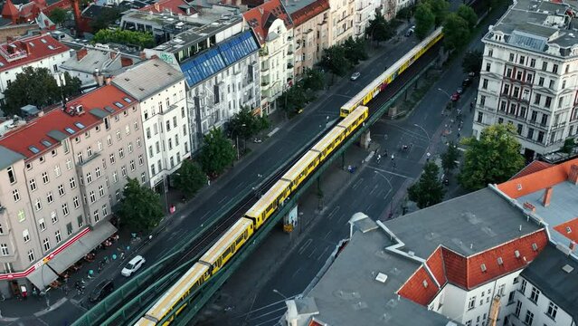 Aerial morning view of train passing . Forwards flying above wide street with Sbahn line tracks. Berlin, Germany