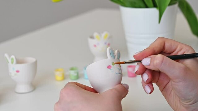Top view on hands painting egg cup shaped as bunny. Easter concept	