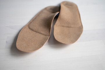 orthopedic insoles for shoes brown, made of natural materials, lies on a light surface of the table. Prevention and treatment of flat feet, shoe accessories