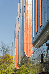 Kolorowy detal na elewacje obiektu, budynku. Materiał z pionowych aluminiowych i pomarańczowych paneli. Nowoczesny budynek. Okna i odbicia - obrazy, fototapety, plakaty