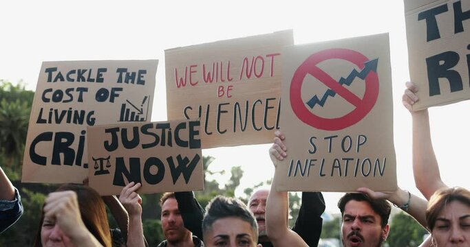 Group of diverse people protest against inflation and financial crisis - Protesters marching for rise cost of living in the city while holding up banners