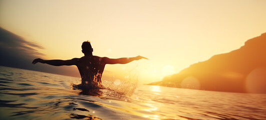 Fototapeta na wymiar A happy young man jumping into the tropical sea at sunset as an image of a happy life on a journey. Sunset over tropical beach and splashing water drops. Summer vacation concept