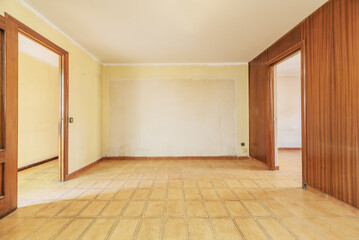 Living room of an empty house with walls covered in varnished sapele wood panels and light brown stoneware floors