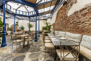 A dining room of a restaurant decorated in an industrial style and with a large skylight with a metal structure