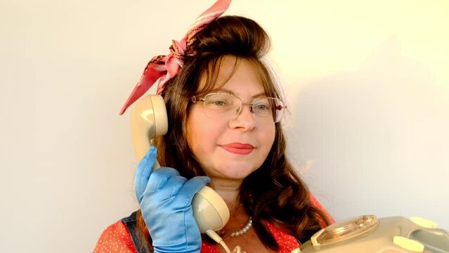 woman with long hair in glasses, pink headband, blue gloves in retro pin-up style, pin-up look speaks on dial telephone, handset in hand, concept pop art style, call to hotline, retro technologies