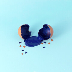Eggshell with blue paint. Creative copy space on blue background. Minimal Easter holiday concept.