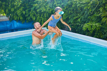 Father and daughter have fun in swimpool at home