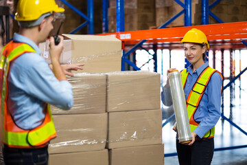 Caucasian team man and woman worker working at warehouse factory. Warehouse staff worker are helping to wrap the shock absorber on the container box