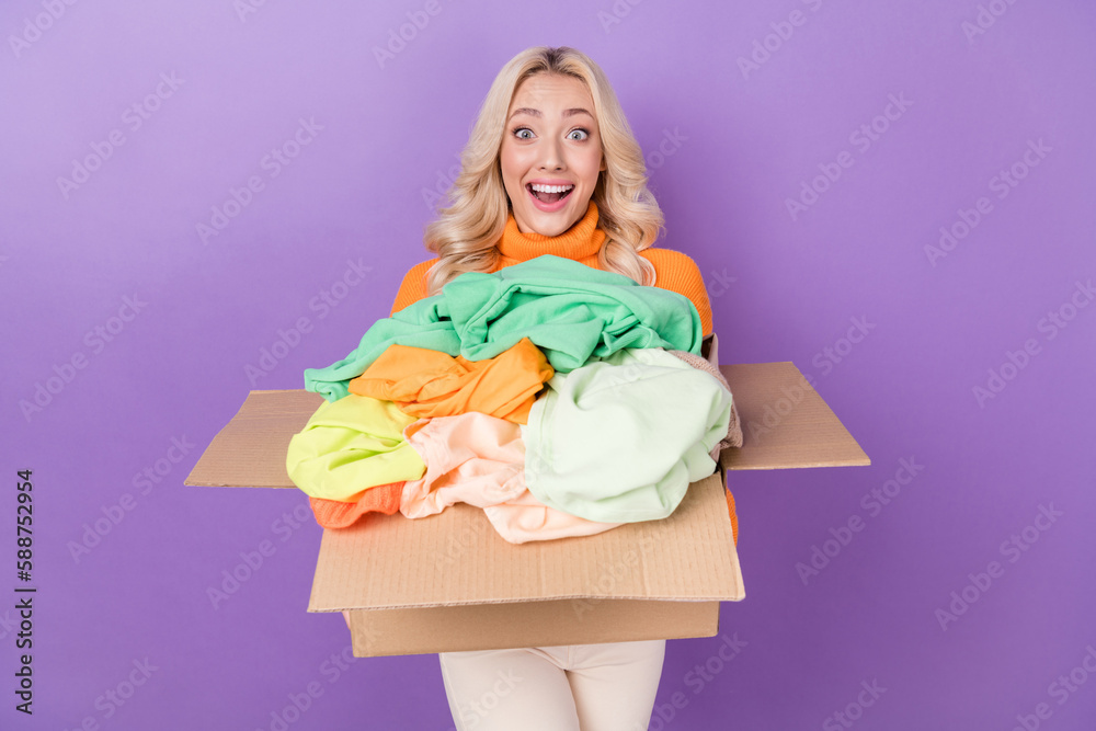 Poster photo of astonished funky girl hold carton box pile stack clothes isolated on violet color backgroun