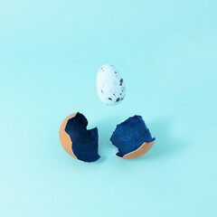 Cracked shell with blue egg on color background. Food concept.