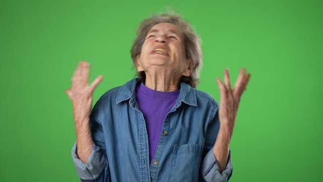 Angry, scared elderly senior old woman with wrinkled skin and grey hair put hands out ask why me, isolated on green screen background studio. People lifestyle concept.