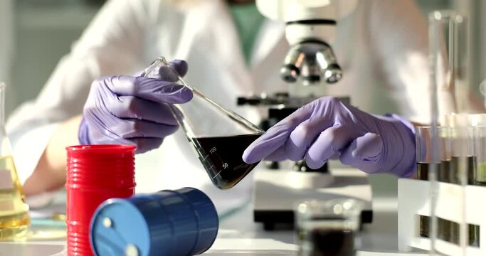 Scientist in chemical laboratory holds black liquid in tube. Analysis and experiment to improve quality of gasoline