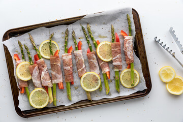 A sheet pan filled with prosciutto wrapped asparagus ready to go in the oven.