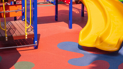 Yellow Slide with Playground Climbing Equipment on Colorful Rubber Floor in Outdoors playground area