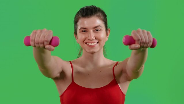 woman lifting dumbells for strong arms dressed red top and sports leggings Isolated on Green Screen studio