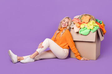 Obraz na płótnie Canvas Full body photo of pretty lady sitting floor pile stack clothes carton box isolated on violet color background