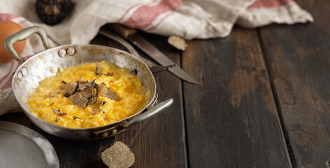 Scrambled eggs with fresh black truffles from Italy served in a frying pan, close up, copy space