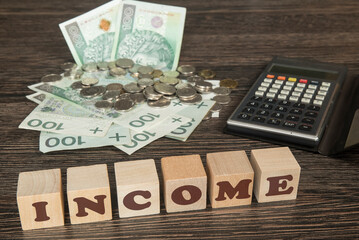 banknoty, bilon wraz z kalkulatorem na stole. Klocki drewniane z napisem INCOME © siwyk