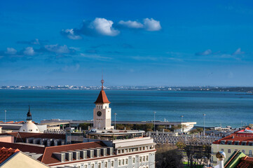 Obraz premium A panoramic view of Lisbon, Portugal, from the Miradouro de Santa Catarina, overlooking the Tagus River and the 25 de Abril Bridge.
