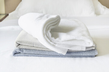 three folded clean terry towels on white background. stack of towels in pastel colors on bedsheet