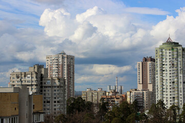 High-rise residential buildings and an industrial plant with a pipe around a green park in a modern city