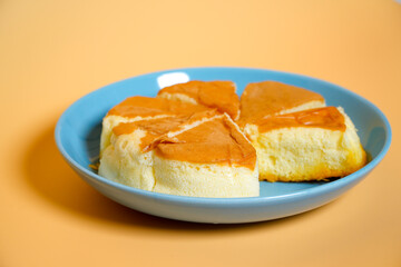 Chiffon cake with young coconut on blue plate, orange background