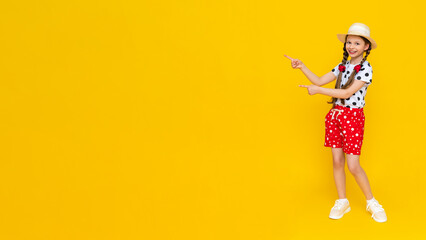 A beautiful girl dressed in summer clothes points to an empty copy space highlighted on a yellow background.