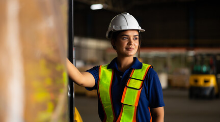 Portrait warehouse indian female worker wearing safety hardhats helmet walking in warehouse of...