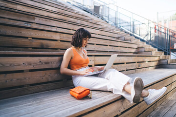 Focused woman working on laptop at street