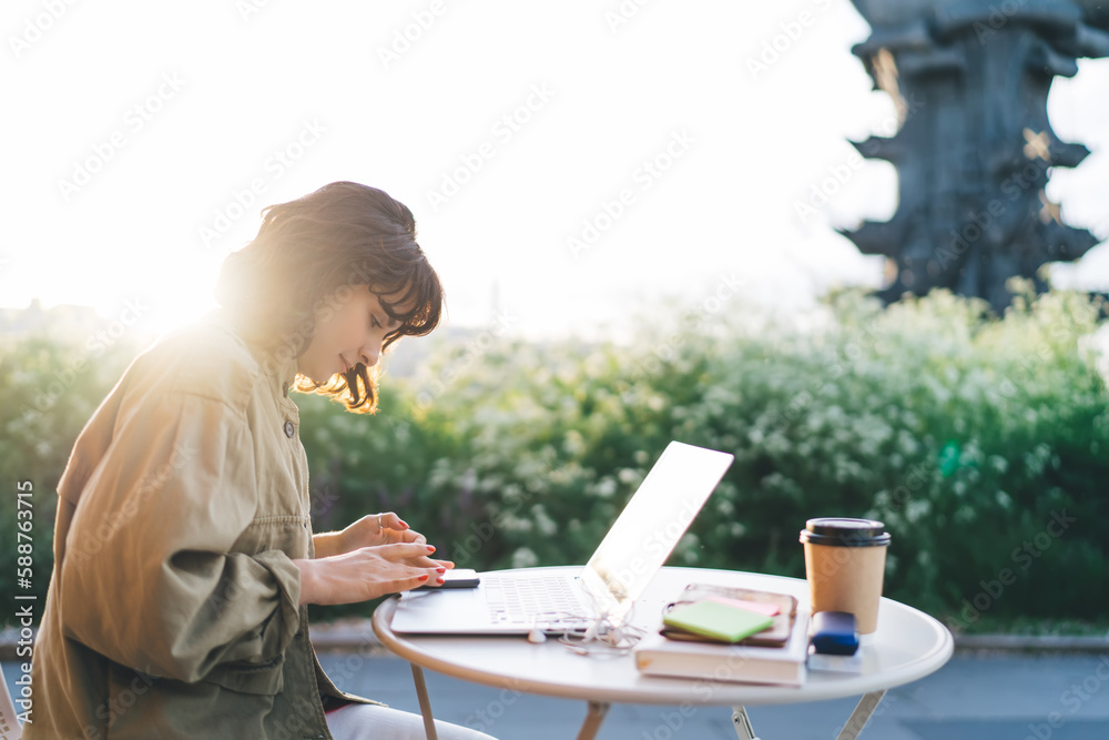 Wall mural Focused woman using smartphone working in outdoor cafe