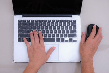 Close up: A woman's hand on laptop keyboard, other hand on mouse.