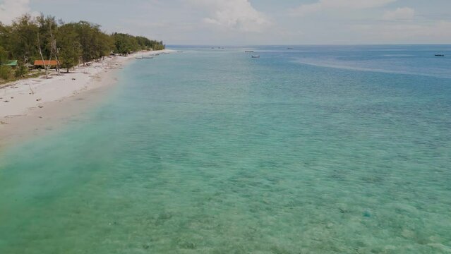 Gili Travangan Island. Beach with local boats and stunning water color. aerial view