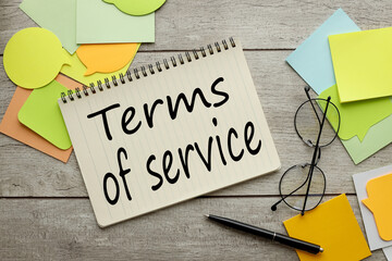 Terms of servise. a lot of stickers are scattered on a wooden background with text on a notepad